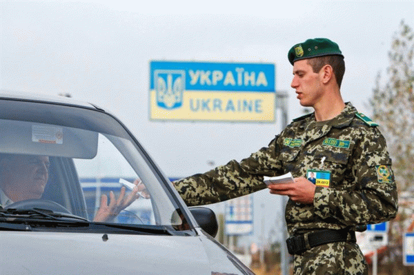 Пограничник проверяет документы водителя на украинской таможне
